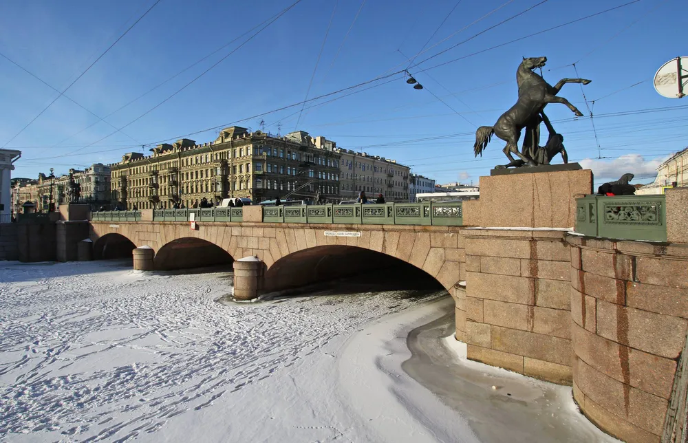 Зимний вид на Аничков мост со скульптурой Клодта и замерзшей Фонтанкой в Петербурге 