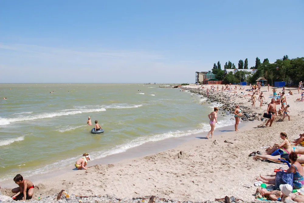 Люди загорают и купаются на песчаном пляже Азовского моря в Ейске
