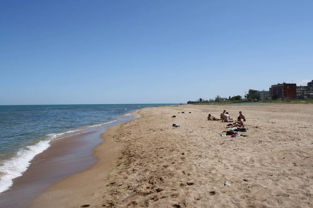 Люди отдыхают на песчаном пляже Каспийского моря в Дербенте, Дагестан