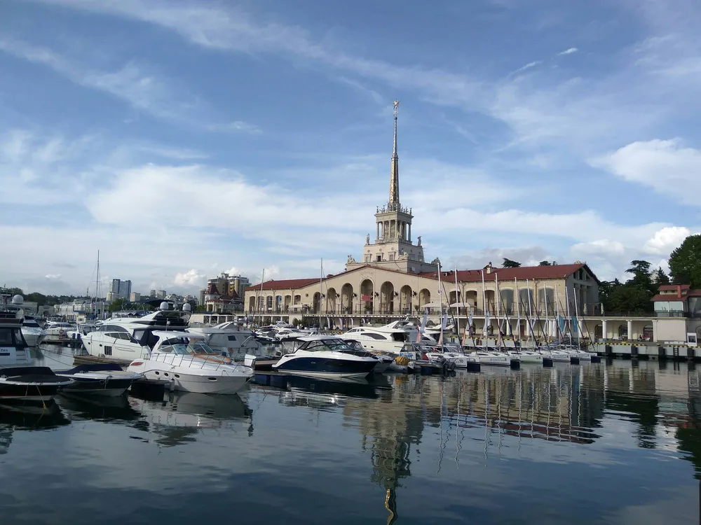 Морской вокзал со шпилем и много белых яхт в порту Сочи