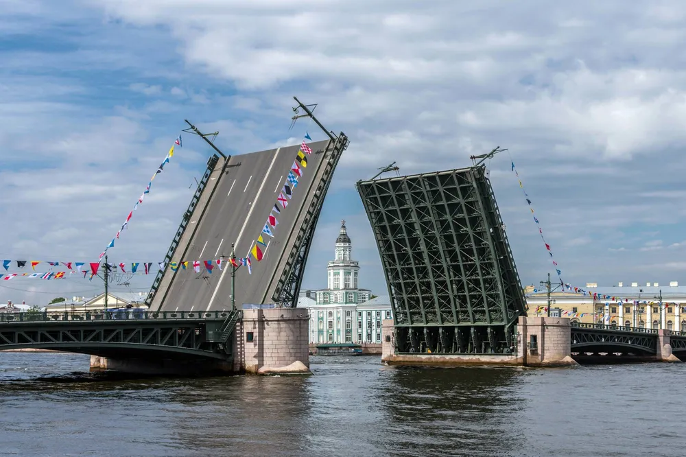 Разведенный Дворцовый мост с флажками на фоне Кунсткамеры в Санкт-Петербурге