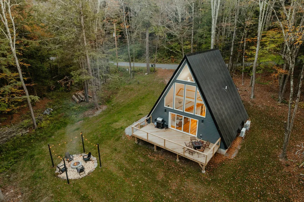 Треугольный домик в виде буквы А A-frame с открытой террасой в осеннем лесу