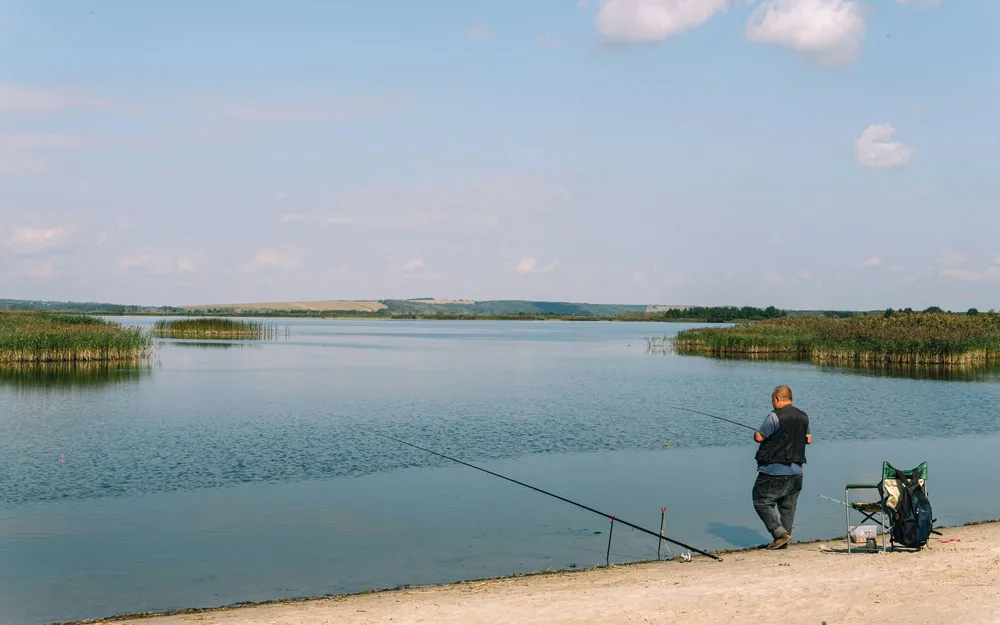Рыбак на песчаном берегу ловит рыбу
